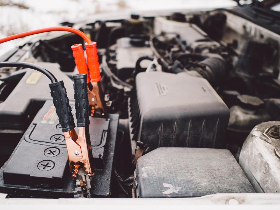 Câbles de survoltage branchés sur une batterie de voiture, neige en arrière-plan
