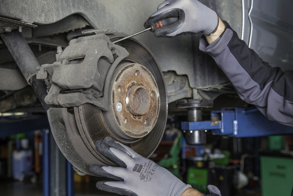 Mains gantées travaillant sur le disque de frein d'une voiture